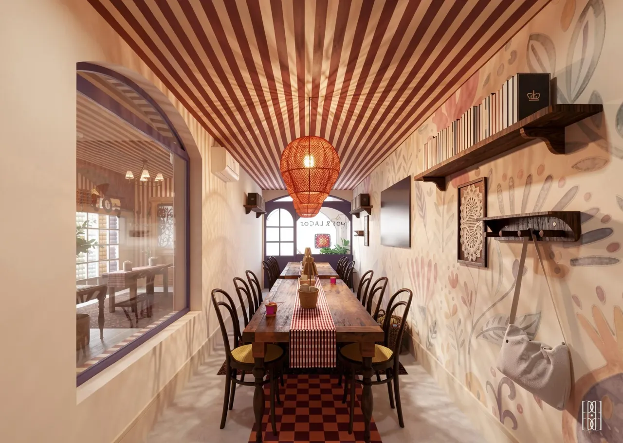 Sala de aulas do café Nós & Laços, com mesa comprida, luminária de vime e parede floral